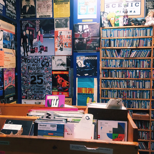 A photo of the interior of a radio station, showing lots of records and CD's and walls covered in posters.